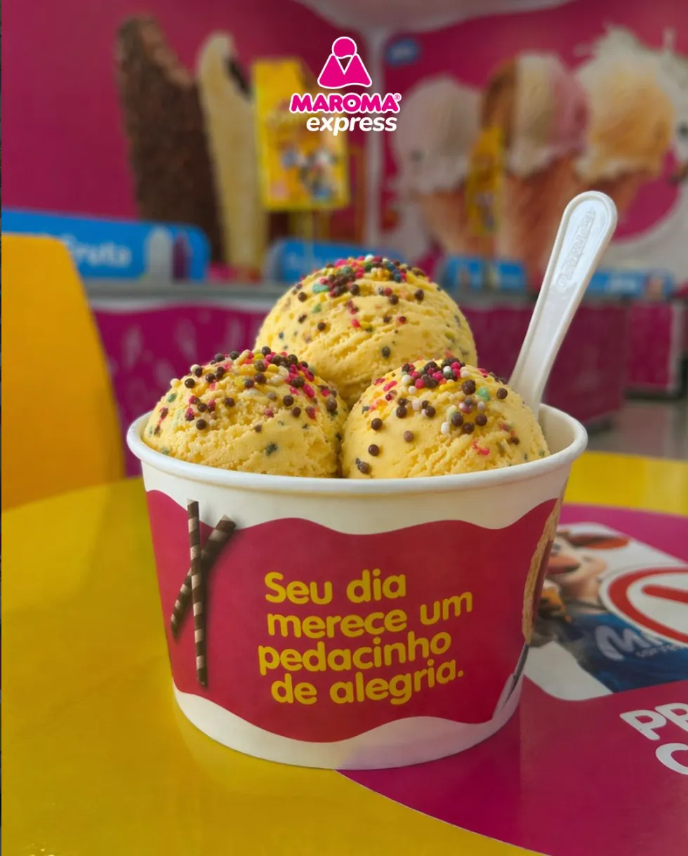 Copinho Maroma com bolas de sorvete e confeitos coloridos e a frase: seu dia merece um pedacinho de alegria